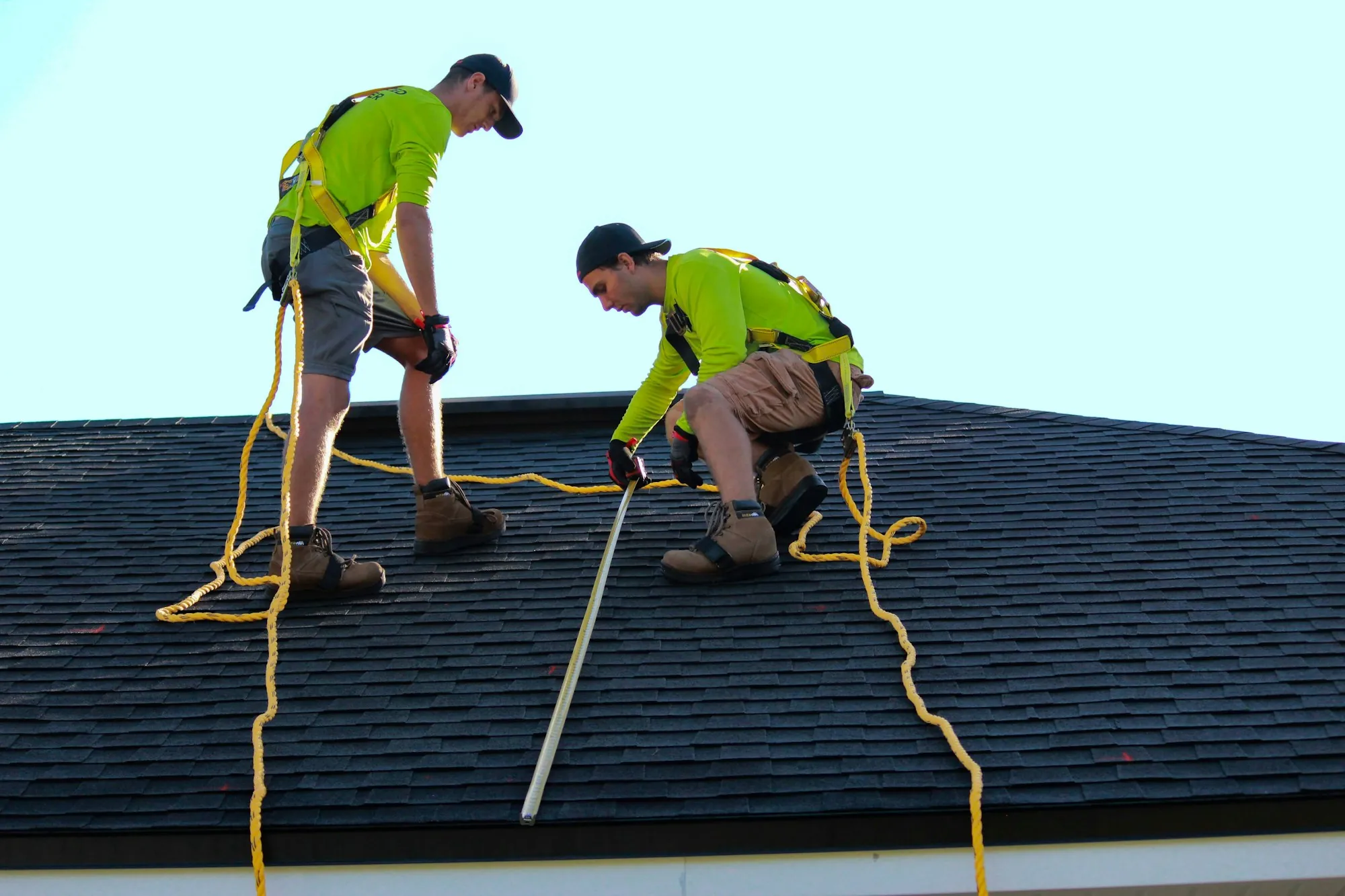 Two roofers checking a residential asphalt shingle roof