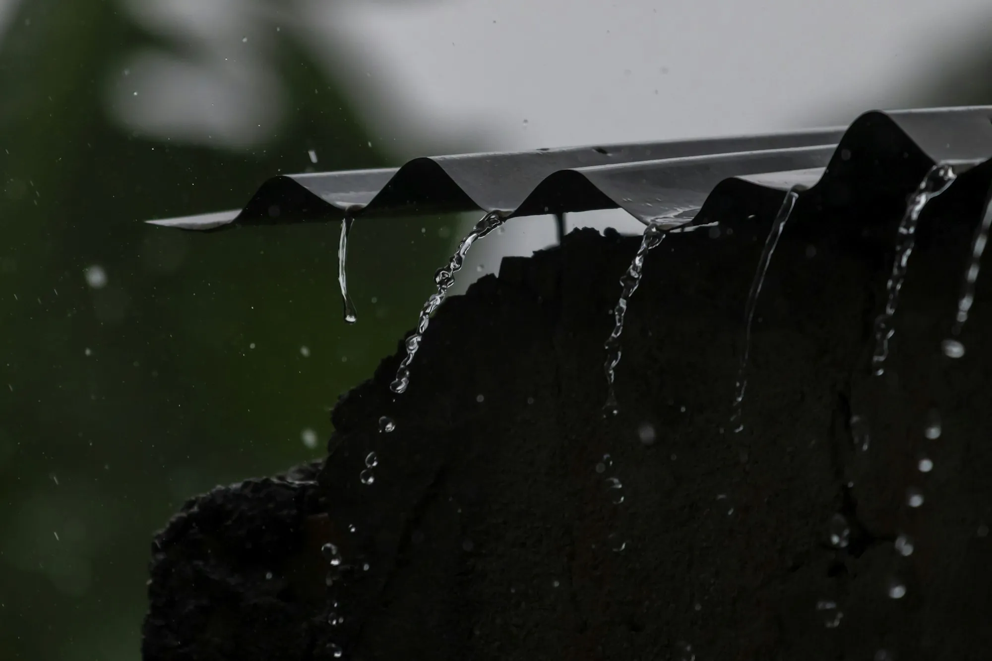 Rainwater pouring off the edge of a dark roof