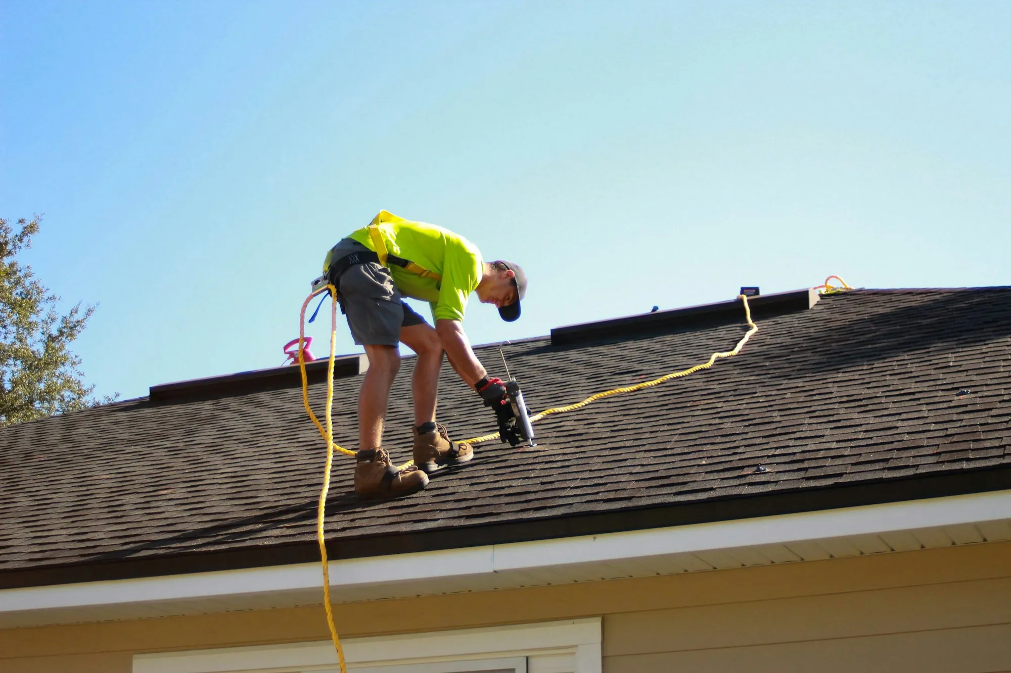 Roofer using a drill while working on a house roof