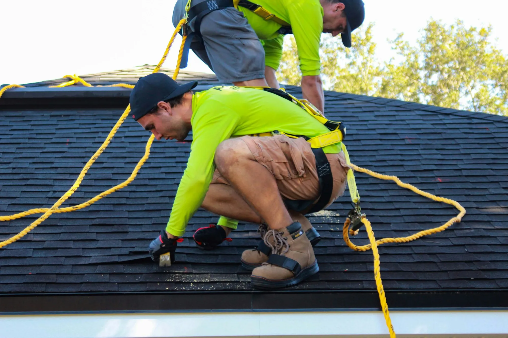 Two roofers working on the roof of a house